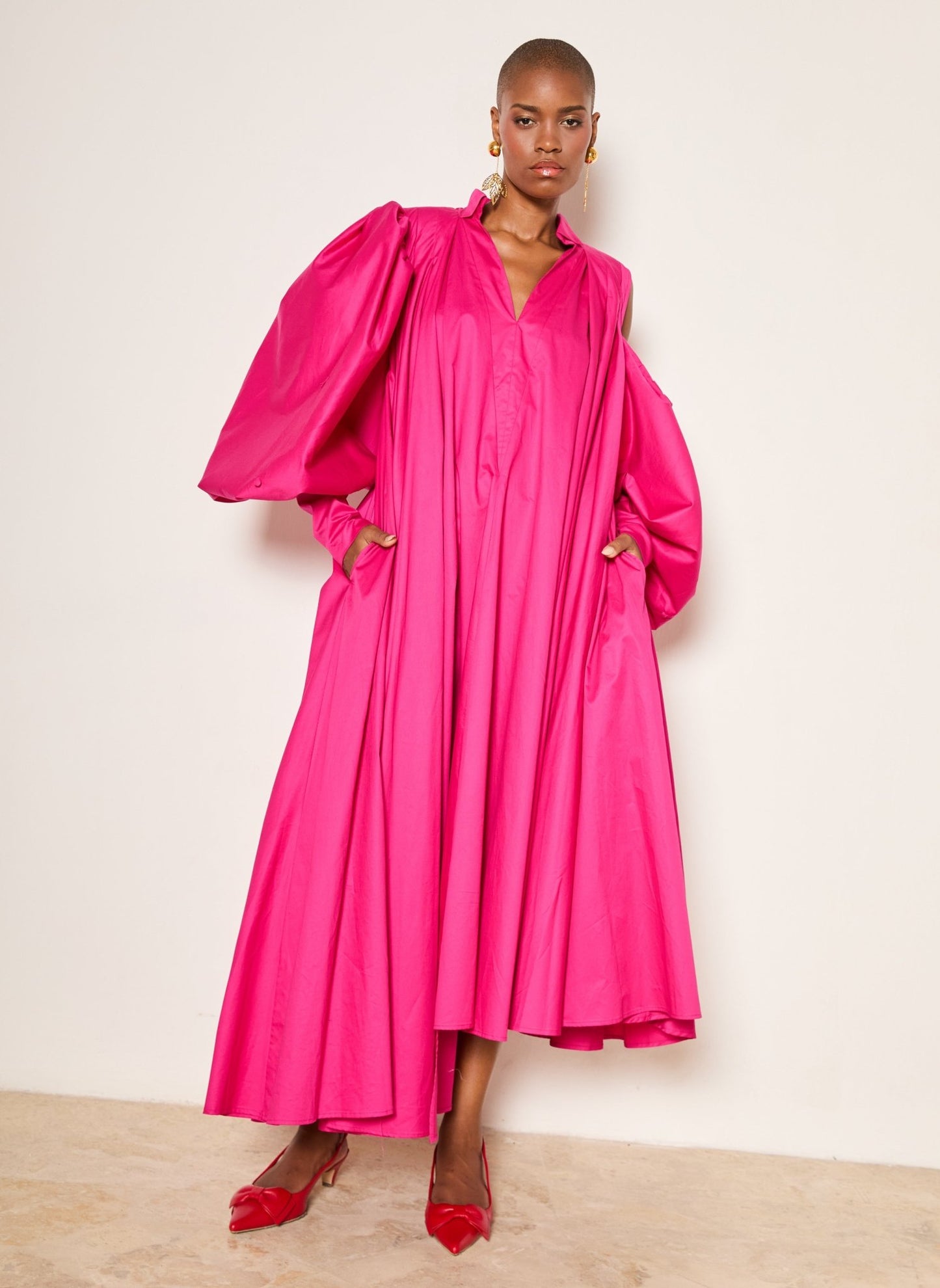 Trapeze Cotton Poplin Gown with oversized puff sleeves, asymmetrical pleated cold shoulder, and side seam pockets, perfect for garden parties and formal events